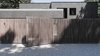 Modern home with Exterior, Tiny Home Building Type, Flat RoofLine, Shingles Roof Material, House Building Type, Metal Roof Material, Brick Siding Material, and Wood Siding Material. Massive wooden fence, which is a stripe, is on the background of a brick house, which is a square. Photo 2 of The Grey House