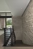 Modern home with Staircase, Metal Tread, Metal Railing, and Wood Tread. Soaring 20 feet from the lower-level floor to the underside of the main floor ceiling, this 2017 Franklin home features a magnificent wall constructed of split-faced Indiana limestone of varying heights. This feature wall is the perfect backdrop for the magnificent black steel and stained white oak floating stairway. The linear pattern of the stone was matched from outside to inside by talented stone masons to laser perfection. The recess cove in the ceiling provides wall washing hidden LED lighting to highlight this feature wall. Photo 3 of Contemporary Michigan Lake Home
