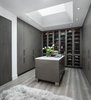 Modern home with Storage Room and Closet Storage Type. The owners of this Franklin home, completed in 2017, wanted a fitted closet with no exposed hanging or shelving but with a lot of drawers in place of a conventional dresser or armoire in the bedroom itself. The glass doors are both functional and beautiful allowing one to view the shoes and accessories easily and also serves as an eye-catching display wall. The center island, with a quartz countertop, provides a place for folding, packing, and organizing with drawers accessed from both sides. Not shown is a similar half of the closet for him and a luggage closet. The designer created splayed shafts for the large skylights to provide natural light without losing any wall space. The master closet also features one of the flush doors that were used throughout the home. These doors, made of European wood grain laminate with simple horizontal grooves cut in to create a paneled appearance, were mounted with hidden hinges, no casing, and European magnetic locks. Photo 6 of Contemporary Michigan Lake Home