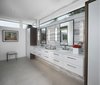 Modern home with Bath Room, Pendant Lighting, One Piece Toilet, Porcelain Tile Floor, Porcelain Tile Wall, Drop In Sink, Engineered Quartz Counter, and Ceiling Lighting. The master bath in this Franklin home, completed in 2017, features a natural cement looking porcelain floor tile with large format Italian porcelain slabs on the walls to create a natural gray travertine appearance. The wall hung cabinetry is simple yet functional allowing for all items including towels, linens, and dirty laundry to be easily stored in the two towers flanking the countertop. Above the two towers is a ribbon of glass windows to the ceiling which provide ample light while allowing for privacy. The bathroom also features a makeup vanity area with built-in hidden medicine cabinets and a huge walk-in shower with rain head, floating stone seat, and matching floor-to ceiling porcelain slabs on the shower walls. Photo 7 of Contemporary Michigan Lake Home