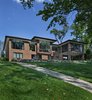 This home in Franklin, completed in 2017, was inspired by the Frank Lloyd Wright Robie House in Chicago and uses linear design materials including large overhangs and a shallow sloped hip roof. The exterior materials feature a norman style brick with colored mortar, tooled horizontal joints, and filled vertical joints, as well as long pieces of Indiana split-faced limestone in varying heights. The siding and fascia are wire-brushed African mahogany with a smooth mahogany reveal between boards. The windows are full height to the bottom of the stuccoed soffits that also feature hidden ventilation. The motor court features a combination of exposed aggregate and sawcut concrete while the entry steps are porcelain tile. The magnificent white oak and glass entry system continues the horizontal linear theme. The metal edges on the roof conceal gutters while downspouts are hidden inside the structure leaving a clean roofline. The house is situated on a hill that rolls toward the lake and features a walkout lower level giving it a two story appearance in the rear. The 12’ high dining room windows in the center of the house are framed in African mahogany with a larger overhang. The large kitchen window and floor-to-ceiling windows in the master bedroom and sitting room, tucked beneath the ample overhangs, complete the look. Photo 19 of Contemporary Michigan Lake Home modern home
