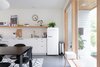 Modern home with Kitchen, Open Cabinet, Range, Dishwasher, Engineered Quartz Counter, White Cabinet, Concrete Floor, Refrigerator, Microwave, Ceiling Lighting, and Undermount Sink. The kitchen was designed to blend with the open floor plan. The SMEG refrigerator was chosen to feel like a piece of furniture and many of the household items add a sculptural quality. Photo 7 of 111 House