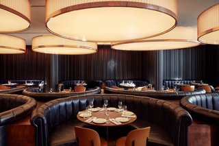 Immense cylindrical lights hang over semi-circular banquette seating in Mr. Porter.