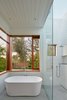 A large skylight above the shower and a generous sliding glass panel open the bathroom to the landscape beyond, creating an indoor-outdoor bathing experience. Photo 4 of Modern-Day California Ranch House modern home
