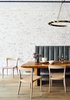 Modern home with Dining Room, Light Hardwood Floor, Chair, Table, Bench, and Pendant Lighting. A custom designed built-in tufted banquette creates a soft, lush seating area at the live edge dining table. The velvet upholstery contrasts the exposed white-washed original brick in both texture and era. Overhead a brass chandelier with exposed Edison bulbs references the former Swan Incandescent Electric Light Co. which occupied the loft after construction was completed in 1897. Photo 2 of Crosby Loft