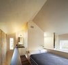 Modern home with Bedroom, Wall Lighting, Plywood Floor, and Bed. The bedroom with open bathroom behind. The volume of the bathroom shears the open geometry of the gabled roof form. Photo 5 of Micro Cabin