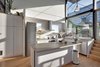 Modern home with Kitchen, Medium Hardwood Floor, Porcelain Tile Backsplashe, Cooktops, Dishwasher, Drop In Sink, Range Hood, Laminate Counter, Refrigerator, White Cabinet, Pendant Lighting, and Range. PLANT Architect Inc. reworked the kitchen in the Berkely Live/Work Residence; it's now an airy, open social area. Photo 2 of Berkley Live-Work Residence