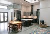 Modern home with Kitchen, Stone Slab Backsplashe, Range Hood, Pendant Lighting, Concrete Floor, Range, Refrigerator, Colorful Cabinet, Undermount Sink, Recessed Lighting, and Engineered Quartz Counter. In the original building, large double doors allowed hydroplanes to move in and out of the space. In keeping with this inspiration, Waldron Designs kept the double door entry with a light and airy transition space.
Ensuring that light could move freely throughout the space was a must. Oversized skylights were used as well as the separation of spaces with glass. In the evening, the interior walls of the skylights have lighting to permit light to always emanate from these spaces. Photo 2 of Vashon Hangar Conversion