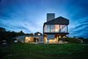 Modern home with Exterior. Elevation looking out over the sheepfold. The cantilevered living room extends over an outdoor fireplace and sitting area, and the smokestack extends through. Photo 20 of Chilmark House