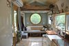 Modern home with Living Room, Sofa, Light Hardwood Floor, and Pendant Lighting. The living room area enjoys a porthole opening to the outdoors. Photo 6 of The San Juan Tiny House