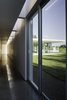 Modern home with Hallway and Concrete Floor. The project is laid out as a series of garden rooms. Privacy is modulated by solid white walls, which extend from deep within the house, into the landscape outside. Material and color choices are restrained, so that the building can be a blank canvas for the play of natural and artificial light. Photo 3 of East Aurora Residence