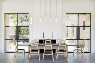In the dining room of the main house, guests perch on black leather and bleached white oak Stahl and Band chairs around Jeff Martin Joinery’s Schoolhouse table fashioned from ebonized oak and bleached and whitewashed ash. Tom Kirk Flute pendants hang overhead.