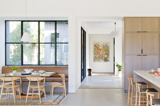 A sculptural bench from the Future Perfect and a circa-1950s vintage blown-glass, brass, and enameled metal Kalmar Tulipan chandelier invite guests through the entry. The space flows into the kitchen, where meals unfold on a built-in banquette upholstered in SH Frank leather by Geremia Design, or CH33T chairs underneath an Atelier Rich Tegelaar Open Meshmatics pendant.
