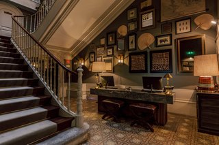 Fans, textiles, and illustrations behind the reception desk, adjacent to the palace's original staircase, transport guests to far-off lands upon entry.