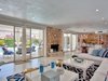 Modern home with Living Room, Standard Layout Fireplace, Recessed Lighting, Rug Floor, Coffee Tables, Ottomans, Light Hardwood Floor, Wood Burning Fireplace, and Sectional. A stone fireplace adds warmth to the large living area. Photo 3 of Arnaz-Ball Residence