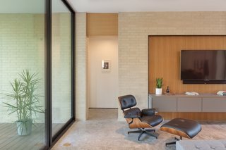 The Eames Lounge Chair in the living area is appealingly positioned by the wall of floor-to-ceiling glass.