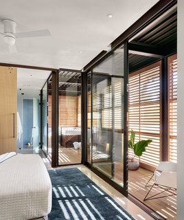 Glass walls bring a sense of brightness to a bedroom and adjacent bathroom.