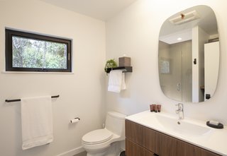 The crisp white bathroom, with a tiled shower enclosed by a glass door.