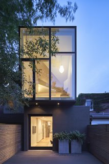 An evening view of the two-story extension, the upper level hovering above the lower.