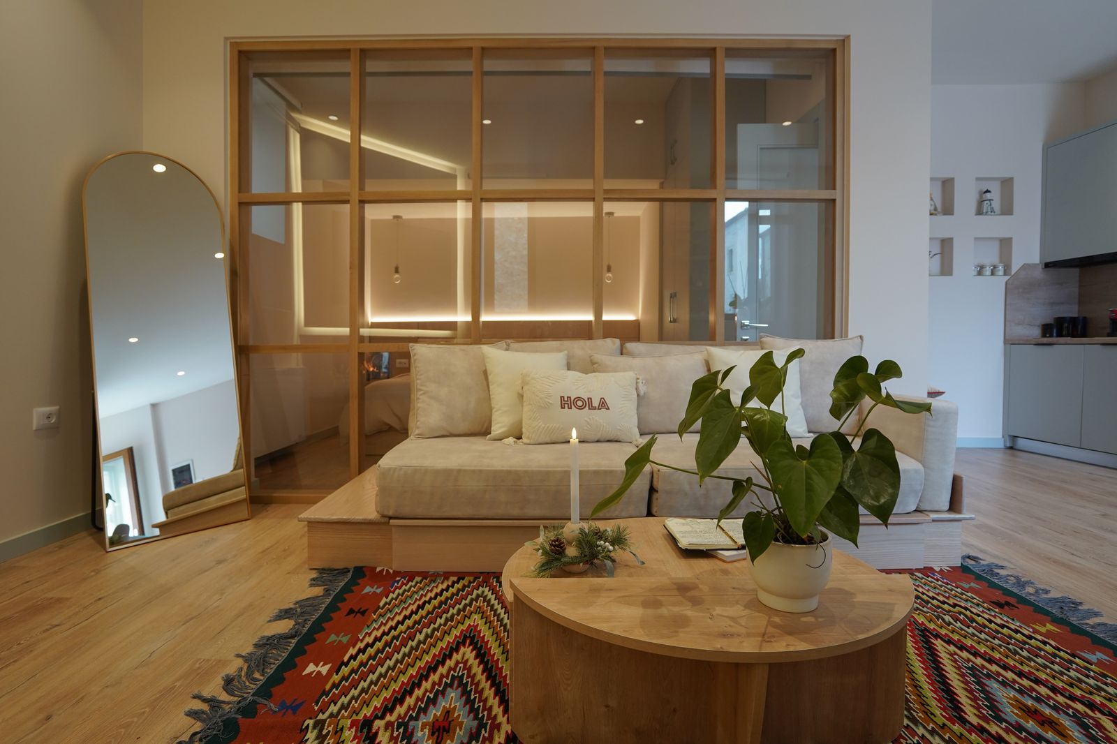 A glass partition separating the living room and bedroom is a defining feature of the living room.