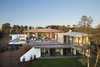 Modern home with Exterior, Glass Siding Material, House Building Type, Curved RoofLine, Brick Siding Material, Stone Siding Material, Flat RoofLine, Green Roof Material, Metal Siding Material, Concrete Siding Material, Metal Roof Material, and Green Siding Material. La Vinya, PGA Golf Resort | Studio RHE Photo of La Vinya, PGA Golf Resort
