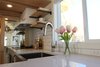 Modern home with Kitchen, Recessed Lighting, Subway Tile Backsplashe, Quartzite Counter, Undermount Sink, Range Hood, Laminate Floor, Cooktops, Pendant Lighting, and White Cabinet. The kitchen features a large sliding window, stainless apron front sink, sparkling quartz counter tops and a modern pull down faucet. The abundance of counter space is key in this L-shaped kitchen. Photo 13 of Innisfree Anarres