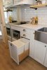 Modern home with Kitchen, Recessed Lighting, Quartzite Counter, Laminate Floor, White Cabinet, Cooktops, Range Hood, Undermount Sink, and Subway Tile Backsplashe. Every inch was planned for in this tiny home including where to put a garbage and recycling. Photo 14 of Innisfree Anarres