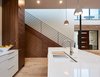 Modern home with Kitchen, Engineered Quartz Counter, Ceiling Lighting, White Cabinet, Undermount Sink, Wood Cabinet, and Light Hardwood Floor. Kitchen looking toward stair with integrated cabinetry Photo 10 of MM31