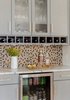 Modern home with Kitchen, Colorful Cabinet, Wood Cabinet, Marble Counter, Light Hardwood Floor, Mosaic Tile Backsplashe, and Beverage Center. The bar adjacent the dining space highlights some whimsy with this unique backsplash made from wood penny tiles stained in different colors to match the rest of the wood tones in the home. Photo 6 of Mid Century Style