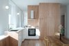 Modern home with Kitchen, Medium Hardwood Floor, Wood Cabinet, Wood Counter, Wall Lighting, Refrigerator, and Cooktops. the kitchen is at the center of the living space Photo 3 of Corner apartment in Strasbourg, France
