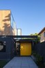 Modern home with Doors, Folding Door Type, Exterior, and Wood. The exterior walls on the first floor of Virginia House by 2712 / Asociados are painted in a dark, neutral color that contrasts with the bright illuminated interiors and sunny yellow front door. Photo 5 of Virginia House
