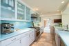 Modern home with Kitchen, Open Cabinet, Dishwasher, Colorful Cabinet, Microwave, Ceramic Tile Floor, Refrigerator, Range Hood, Mosaic Tile Backsplashe, Ceiling Lighting, and Drop In Sink. The sleek kitchen is crafted with blue glass mosaic tile backsplash, custom white cabinetry accented with glass, and world-class stainless steel appliances. Photo 3 of STRANDHUS, A MODERN LIDO SHORES ESTATE