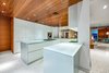 Modern home with Kitchen, Medium Hardwood Floor, Granite Counter, Wood Counter, Vinyl Floor, Wall Oven, Floor Lighting, Dishwasher, Microwave, Ceiling Lighting, Drop In Sink, White Cabinet, Concrete Backsplashe, Stone Counter, Refrigerator, and Ceramic Tile Backsplashe. The premium kitchen, outfitted with opaque glass surfaces, is perfect for entertaining. Photo 4 of Ultra-Contemporary Gulf-to-Bay Estate