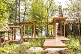 When designing Camp on Long Lake, Winkelman Architecture was inspired by the oak grove the home is nestled into. A <span style="font-family: Theinhardt, -apple-system, BlinkMacSystemFont, "Segoe UI", Roboto, Oxygen-Sans, Ubuntu, Cantarell, "Helvetica Neue", sans-serif;">covered walkway with views of the lake lightly tethers the kitchen, living room, and dining area to the bedroom.</span>