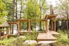 Modern home with Outdoor, Post Lighting, Boulders, Walkways, Shrubs, Wood Patio, Porch, Deck, Landscape Lighting, Front Yard, and Trees. When designing Camp on Long Lake, Winkelman Architecture was inspired by the oak grove the home is nestled into. A covered walkway with views of the lake lightly tethers the kitchen, living room, and dining area to the bedroom. Photo of Camp on Long Lake