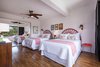 Modern home with Bedroom, Accent Lighting, Laminate Floor, Bed, Dresser, Night Stands, Medium Hardwood Floor, Wall Lighting, Ceiling Lighting, and Storage. Double queen guest bedroom with pops of coral and Hawai'ian decor. Photo 7 of Maui Modern, Budget-Luxury Remodeled Vacation Rental