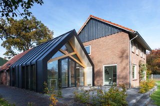 For the extension, Bureau Fraai decided to extend the current old barn next to the farmhouse. While the existing barn was built from bricks and ceramic roof tiles, the façade and roof of the extension are made of black pre-weathered titanium zinc with hidden aluminum window frames that give it a bold and modern feel. 