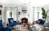 Modern home with Living Room, Chair, Pendant Lighting, Medium Hardwood Floor, Coffee Tables, Sofa, and Gas Burning Fireplace. Designers and homeowners Kele Dobrinski and Christina Valencia renovated this striking Sacramento residence. The original fireplace in the living room is their pup Murphy's favorite spot to keep warm. Kele's great grandmother's chairs were reupholstered in blue velvet for an added pop of color against the freshly painted white walls. Photo 7 of Modern Spanish Revival