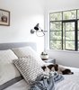 Modern home with Bedroom, Wall Lighting, Bed, and Medium Hardwood Floor. Original metal windows were painted black throughout the house, to maintain the home's original character. Photo 12 of Modern Spanish Revival