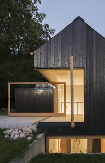 The dark facade that covers Das Schwarze Haus has been preserved through carbonization, instead of through chemical treatment. Buero Wagner's design sits quietly in the countryside, a slender volume rising out of the trees.