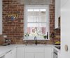 Modern home with Kitchen, Engineered Quartz Counter, Brick Backsplashe, Dishwasher, White Cabinet, and Cooktops. The clean line of Caesarstone bench contracts with the exposed textured brickwork of the original building fabric , now a feature of the kitchen Photo 12 of Preston 1