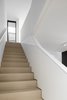 View from the ground floor to the second floor and outdoor lightwell above. The stairs are white stained solid white oak. Photo 11 of Tesseract House modern home