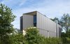 Modern home with Exterior, Wood Siding Material, House Building Type, Metal Siding Material, and Flat RoofLine. View of the front and side of the house from the neighboring lot. The overall form of the home is broken down with light penetrating "carves" into the massing. Photo 2 of Tesseract House