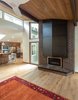 Modern home with Living Room, Ceiling Lighting, Pendant Lighting, Medium Hardwood Floor, Gas Burning Fireplace, and Recessed Lighting. The new steel chimney wrap radiates heat from the new gas-powered fireplace into the living room. Photo of Bellevue Home Remodel