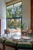 Modern home with Living Room, Chair, Sofa, Sectional, Coffee Tables, and Concrete Floor. A sculptural installation of refurbished teak-wood panels along the double-height main wall adds warmth and colour. The otherwise minimalist room is defined by generously high ceilings and a breath-taking view of the infinity pool and the home’s sprawling gardens. Customised modular furniture in teak wood and muted accents face the accordion glass doors leading outside. Photo 4 of Terra - Earth House - by Kriss Real Estate