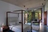 Modern home with Bedroom, Bed, Chair, Ceiling Lighting, Table Lighting, Bench, and Concrete Floor. The top floors of Terra feature two immense master suites with private balconies. One of which is carefully built around the trees that grow densely around it and through it.
The clean lines and selective minimalism of the home's interiors emphasise seamlessly functionality and material efficiency while serving to take a muted backseat to Terra's lush, tropical views. Photo 6 of Terra - Earth House - by Kriss Real Estate