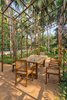 Modern home with Chair. A minimally treated organic wood tabletop sits beneath a metal frame gazebo, which will in time be canopied by the bougainvillaea planted around its edges.
The custom made mid-century chairs reference materials and styles tradtionally seen in colonial Indo-Portuguese designs.
This outdoor dining area overlooks the backyard and the infinity pool (left). Photo 12 of Terra - Earth House - by Kriss Real Estate