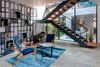An intimate reading nook in Lua's living space features mid-century chairs and a custom made marble-metal geometric bookshelf. The alcove is framed by a floating staircase with grey metal balustrades, a view of an adjacent courtyard and a forward-facing view (not visible here) of the home's double-height accordion glass doors that open into an expansive crescent-shaped pool.
Photo 2 of Lua - The Moon House by Kriss Real Estate modern home
