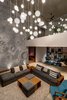 The apex of the home is an awe-striking living room featuring a six-hundred sq. foot wall treated with PoP to replicate the blue-grey surface of the moon. The immense creation is enhanced by a low hanging shooting-star cluster chandelier.
Pool-facing accordion ceiling-height glass doors flank one side of the room. Natural light tempered by reflections on the water and glass floods into the space. The interiors of this living area are deliberately positioned to leverage and manipulate light throughout the day; offering cosy corners hidden by extended shadows and brightly light nooks overlooking the garden, pool and sky. Photo 3 of Lua - The Moon House by Kriss Real Estate modern home