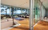 Modern home with Dining Room, Accent Lighting, Table, Stools, Pendant Lighting, Recessed Lighting, Chair, Medium Hardwood Floor, and Ceiling Lighting. View into the open living dining kitchen space and the transparency of the sliding glass doors Photo 9 of North Beach Residence